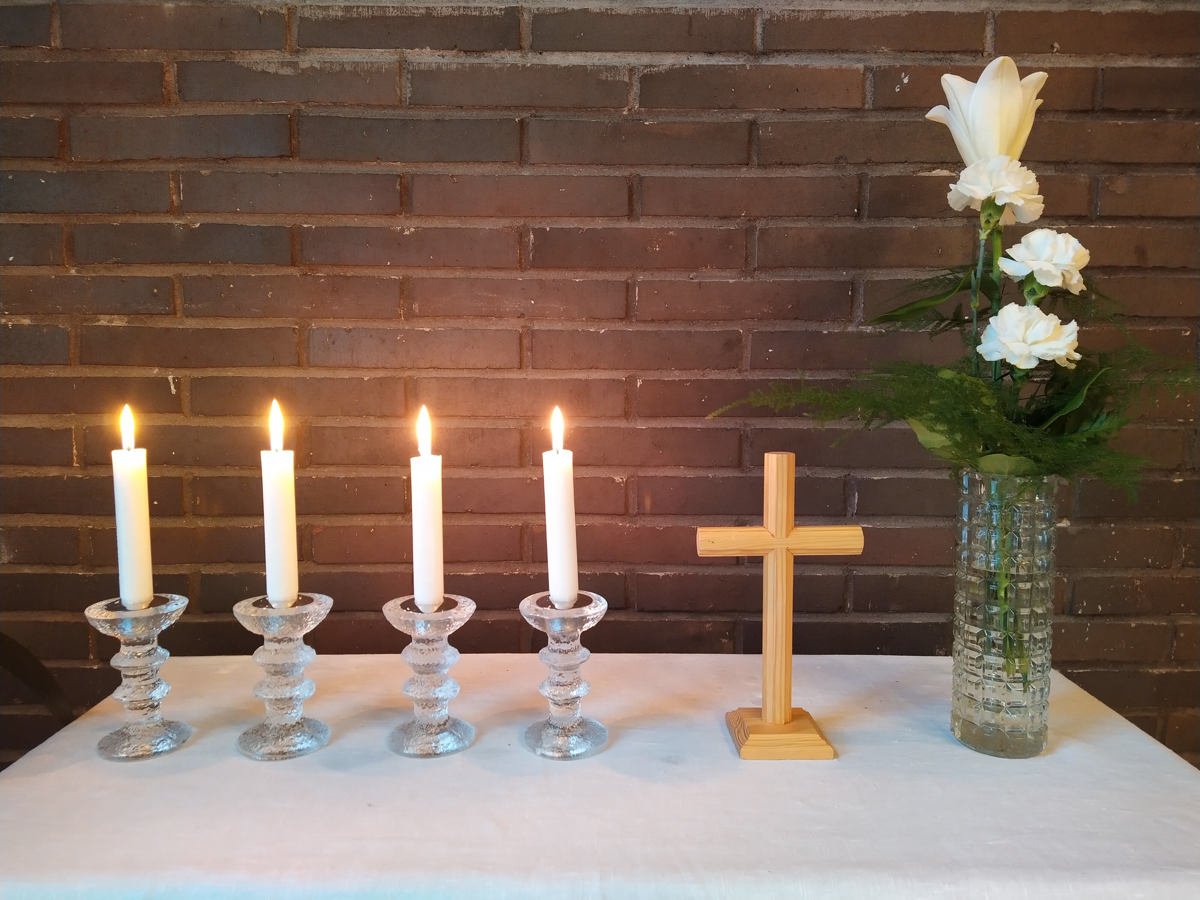 alttarilla neljä kynttilää ja valkoinen lilja maljakossa