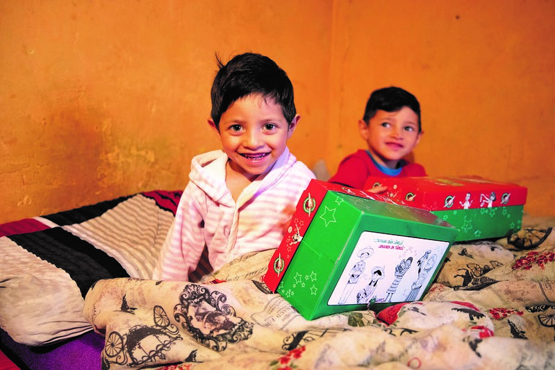 kaksi lasta sängyllä operaatio joulun lapsen lahjojen kanssa.