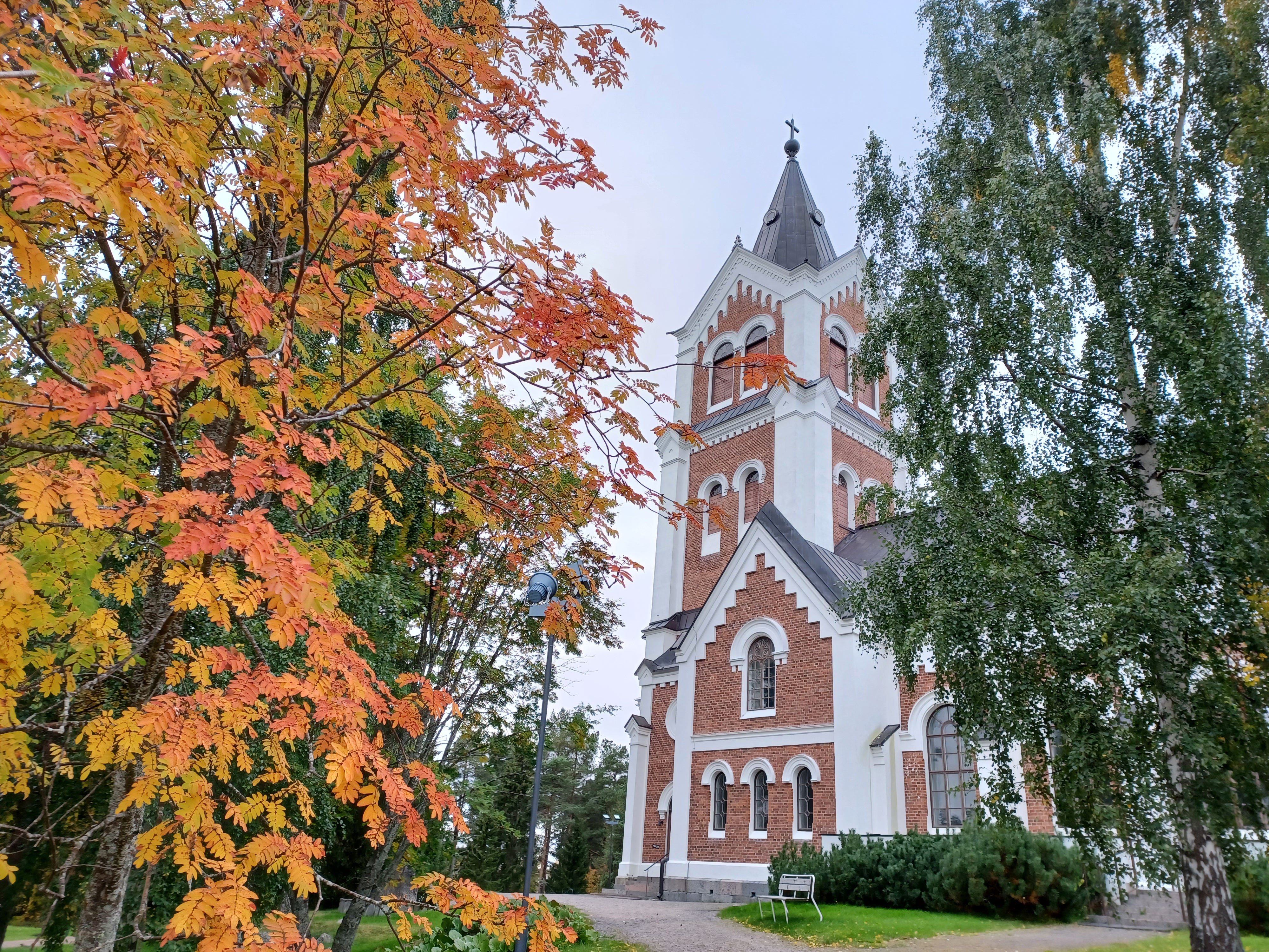 taustalla Lumijoen kirkko, etualalla syksyn väreissä pihlaja ja koivu